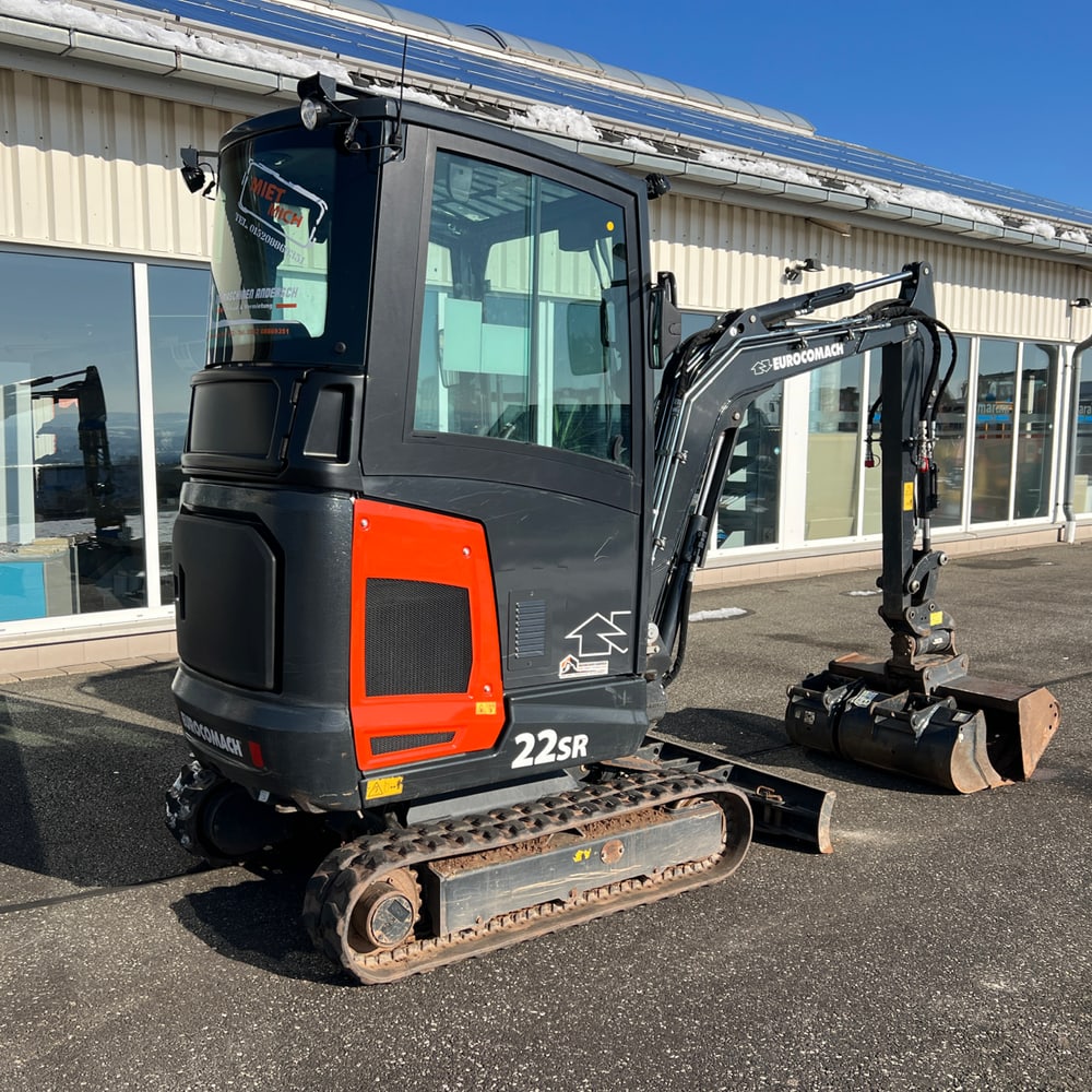 Schwarzer Yanmar Minibagger 22SR mit orangefarbenen Akzenten und Schaufel auf Asphalt.